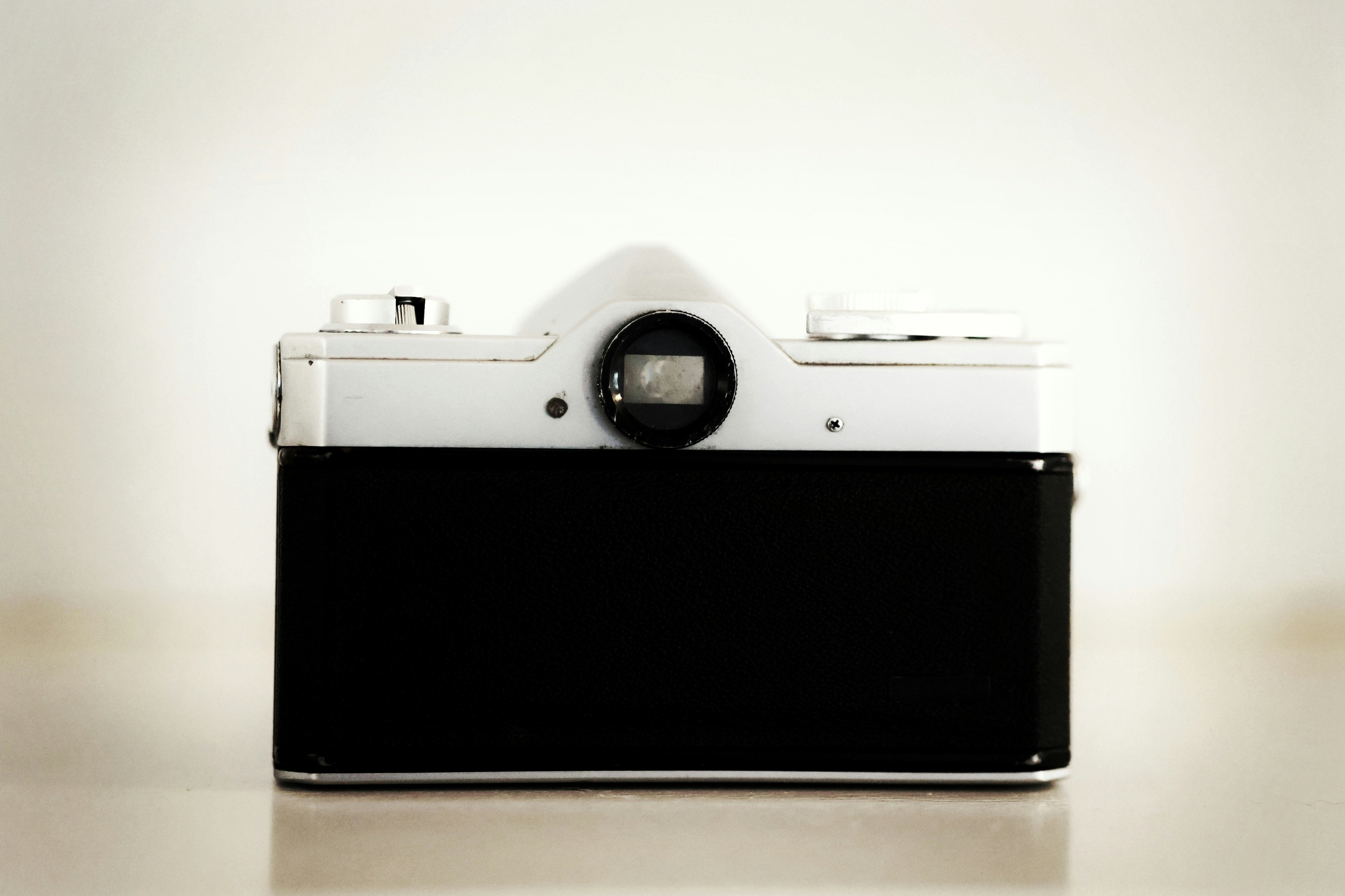 A black rectangular object with a round lens on a white surface photo ...