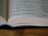 Close-up of hands reviewing a printed book layout on a wooden desk.