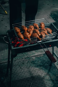 Sizzling tandoori chicken pieces glowing with a smoky red marinade on a grill.