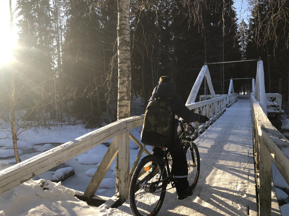 a person riding a bike on a bridge in the snow