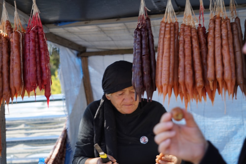 a person holding a bottle of liquid next to a row of sausages