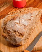 A rustic wooden table with a homemade loaf of bread and a knife.