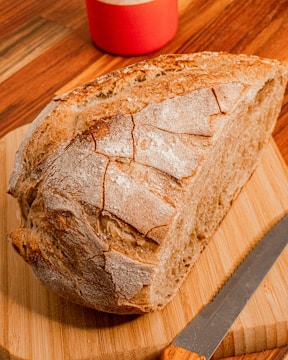A rustic wooden board with freshly baked artisan bread and a knife