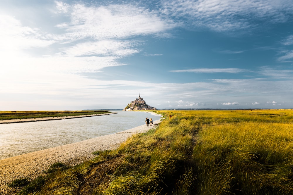 a couple people walking on a path by a body of water