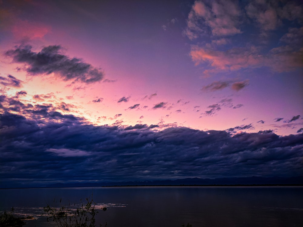 a body of water with clouds above it