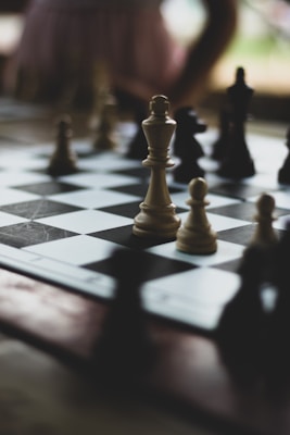 A chess board with pieces arranged for a game, featuring a prominent white king in the middle. The pieces appear to be in focus while the background is blurred, creating a dramatic effect.