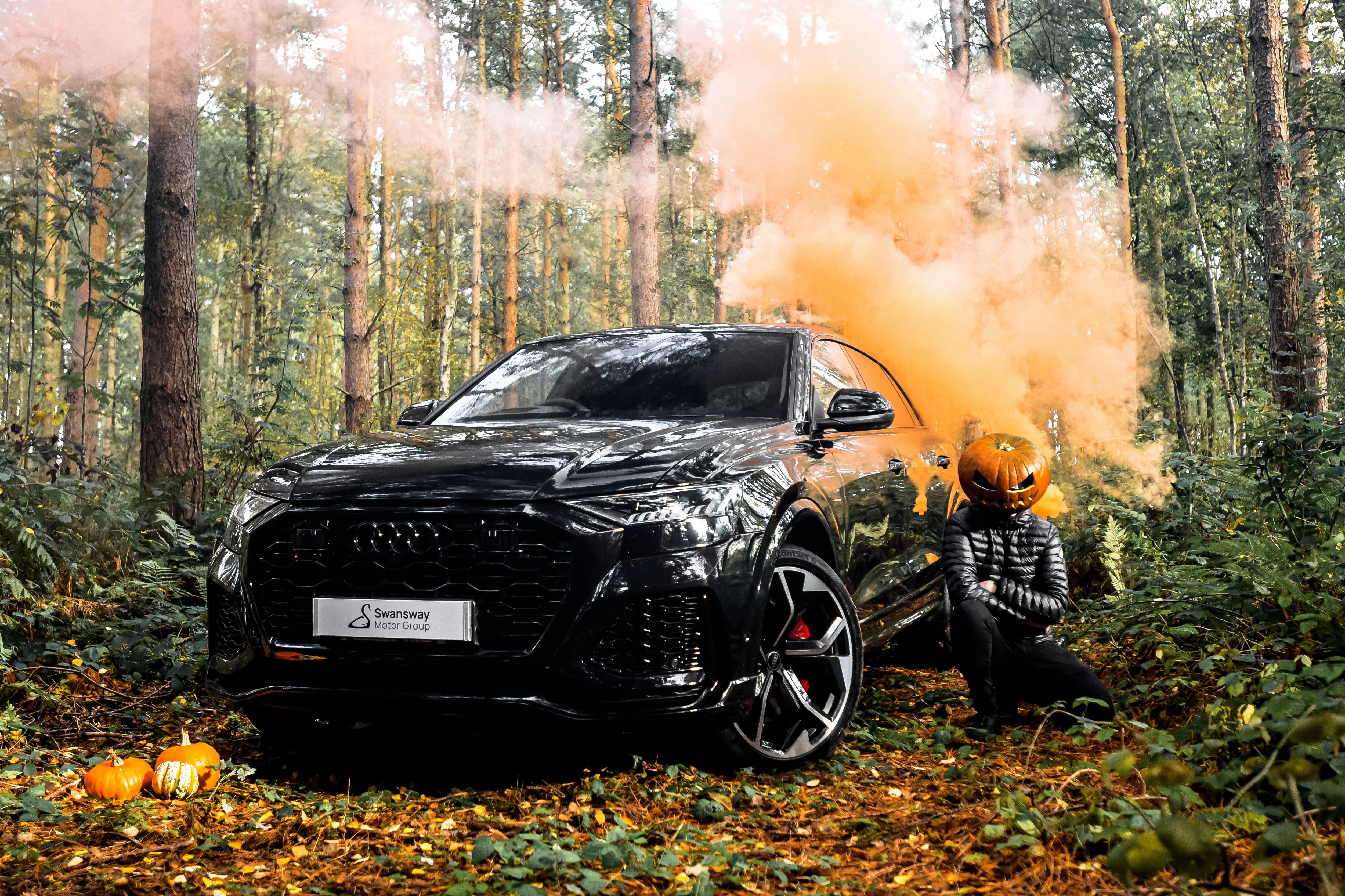 a person kneeling next to a car on fire in the woods