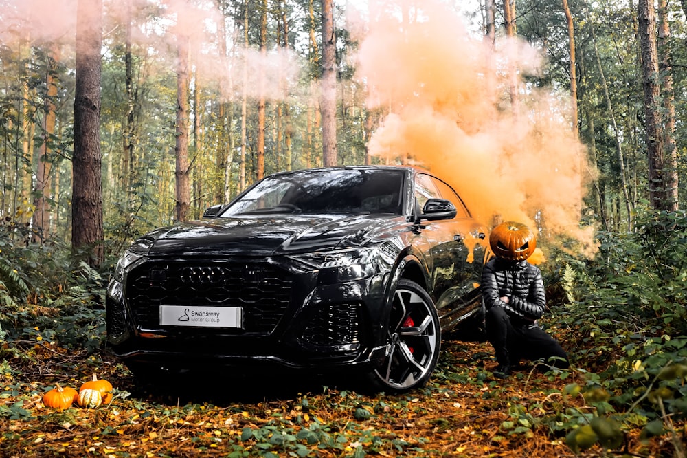 a person kneeling next to a car on fire in the woods