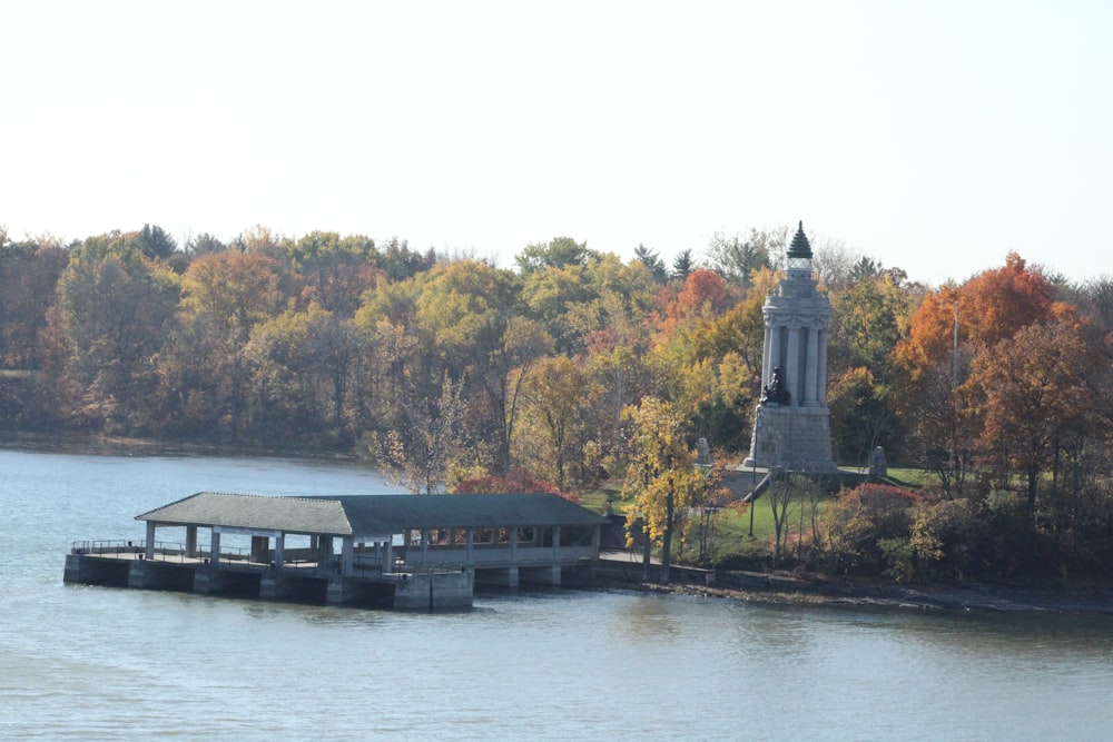 a building on a dock by a body of water with trees in the back