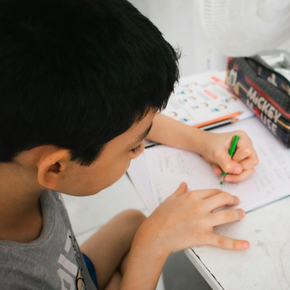 a young boy drawing on a white paper