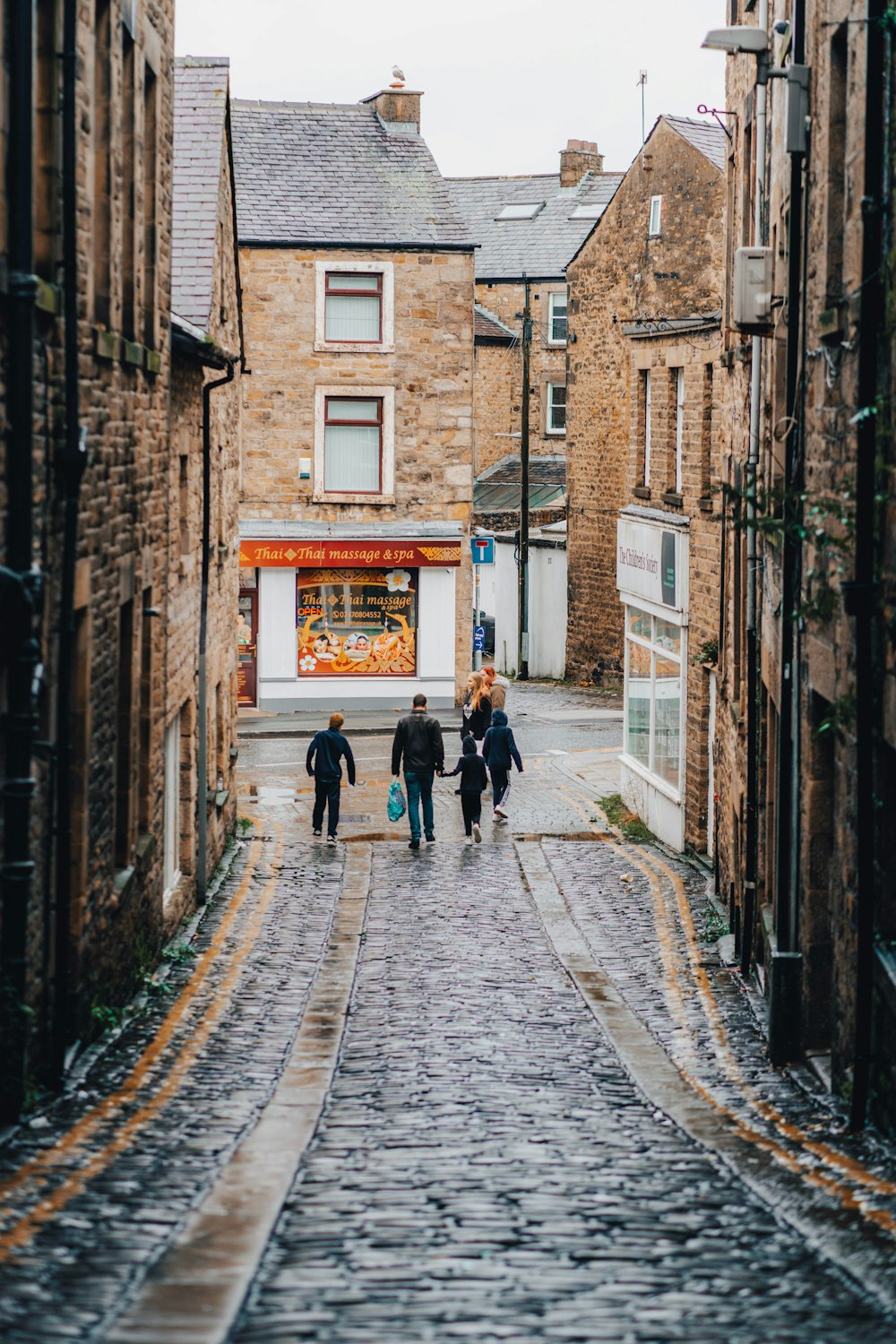people walking on a cobblestone street between buildings