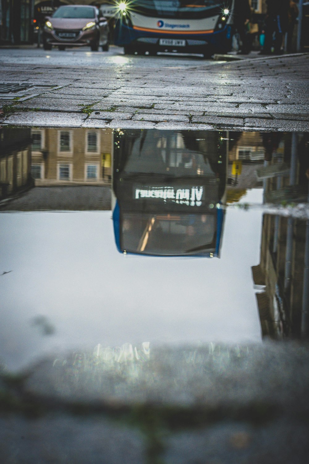 a reflection of a bus in a puddle of water
