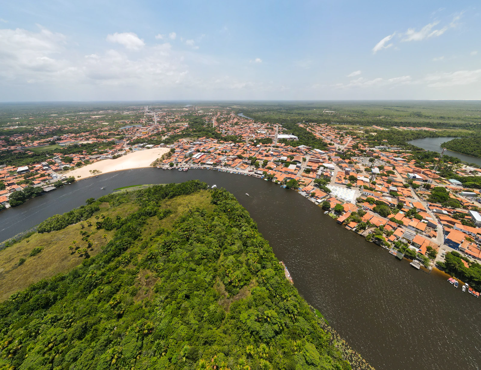 Rio separando a mata da malha urbana, em vista aerea diurna.