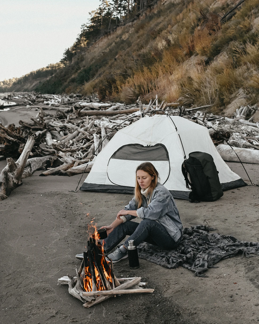 A camper relaxing beside their tent in soft afternoon light