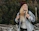 A happy woman carrying a stylish backpack in a city park.
