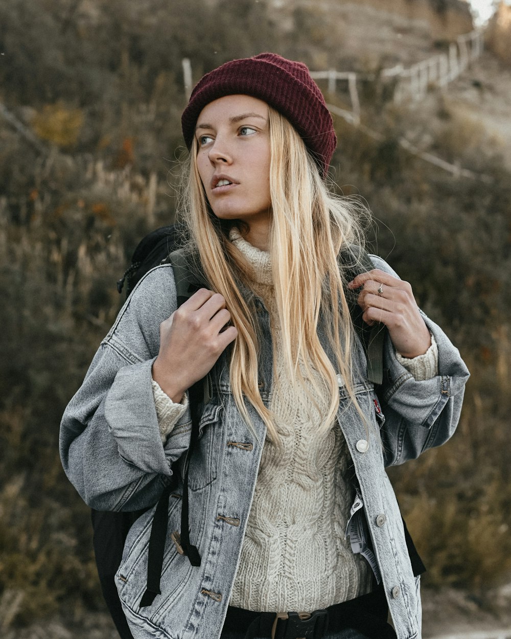 a woman with long hair and a hat holding a cigarette