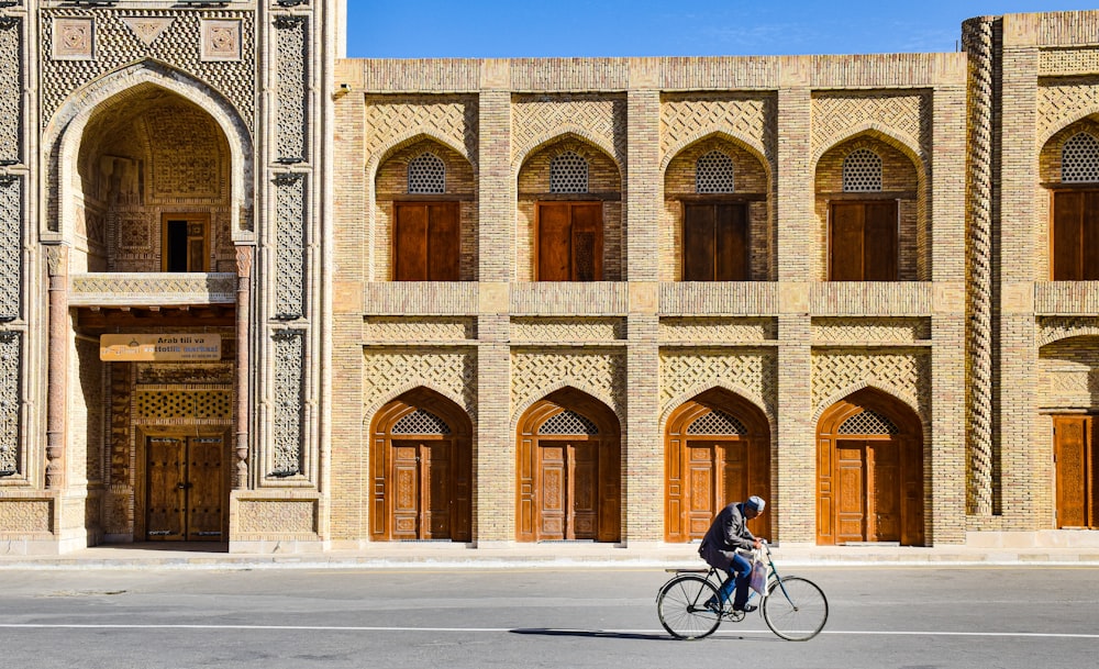 a person riding a bicycle in front of a building