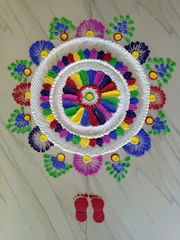 A vibrant rangoli design in bright colors, created by skilled hands on a traditional Indian floor.