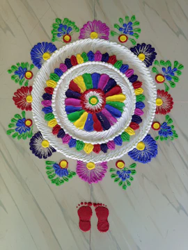 A vibrant rangoli design in bright colors, created by skilled hands on a traditional Indian floor.