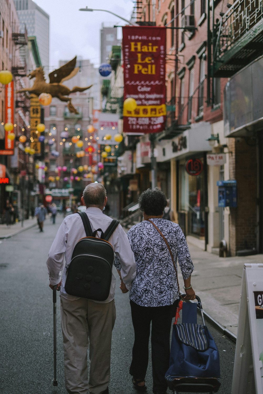 a man and woman walking down a street with signs and lanterns