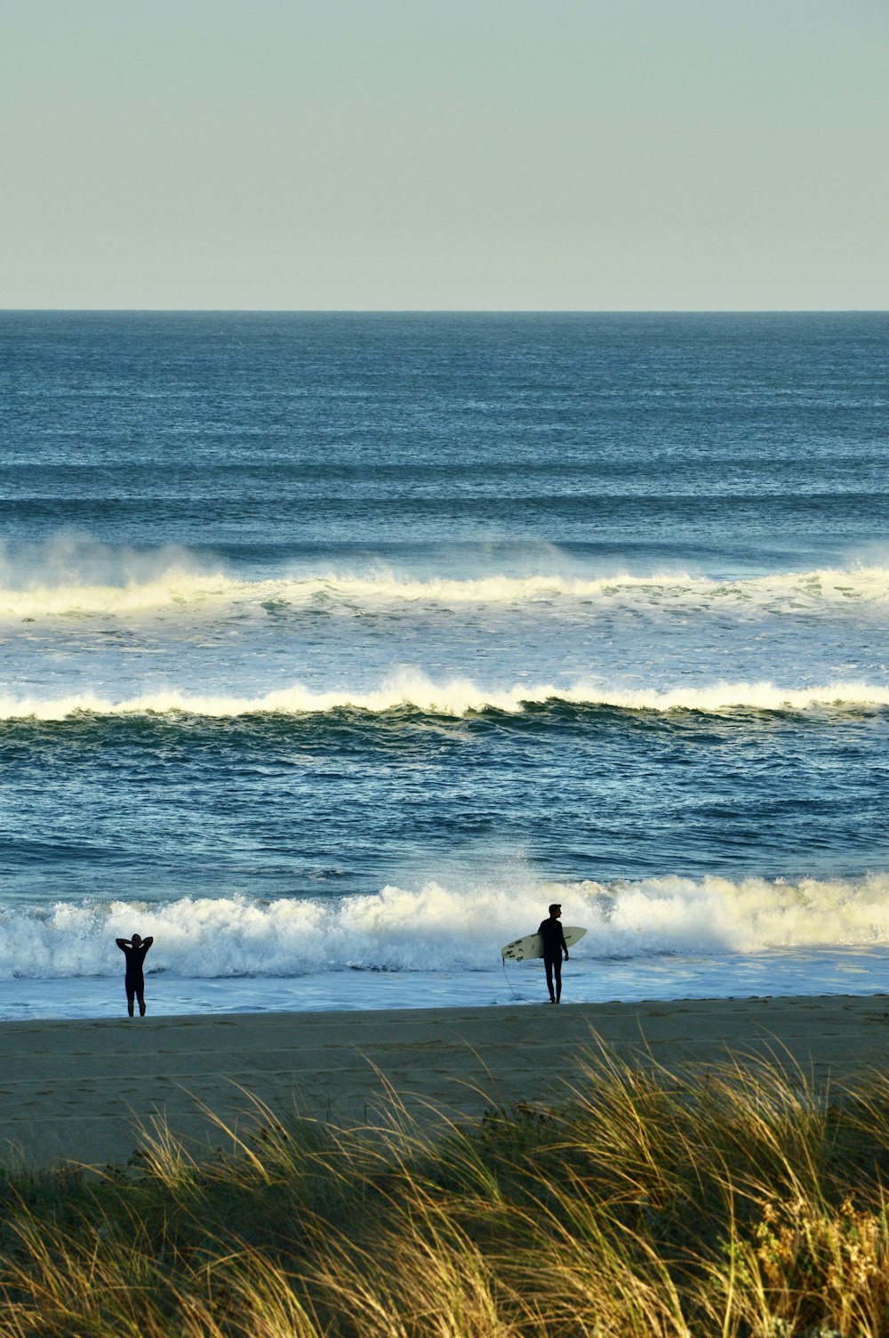 a couple of people stand on a beach with surfboards