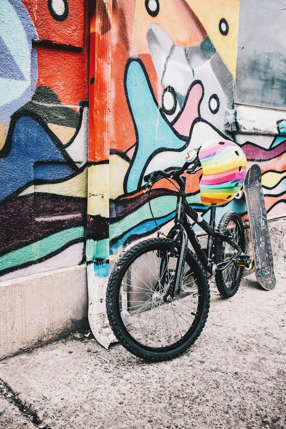 a bicycle is parked in front of a wall covered in graffiti