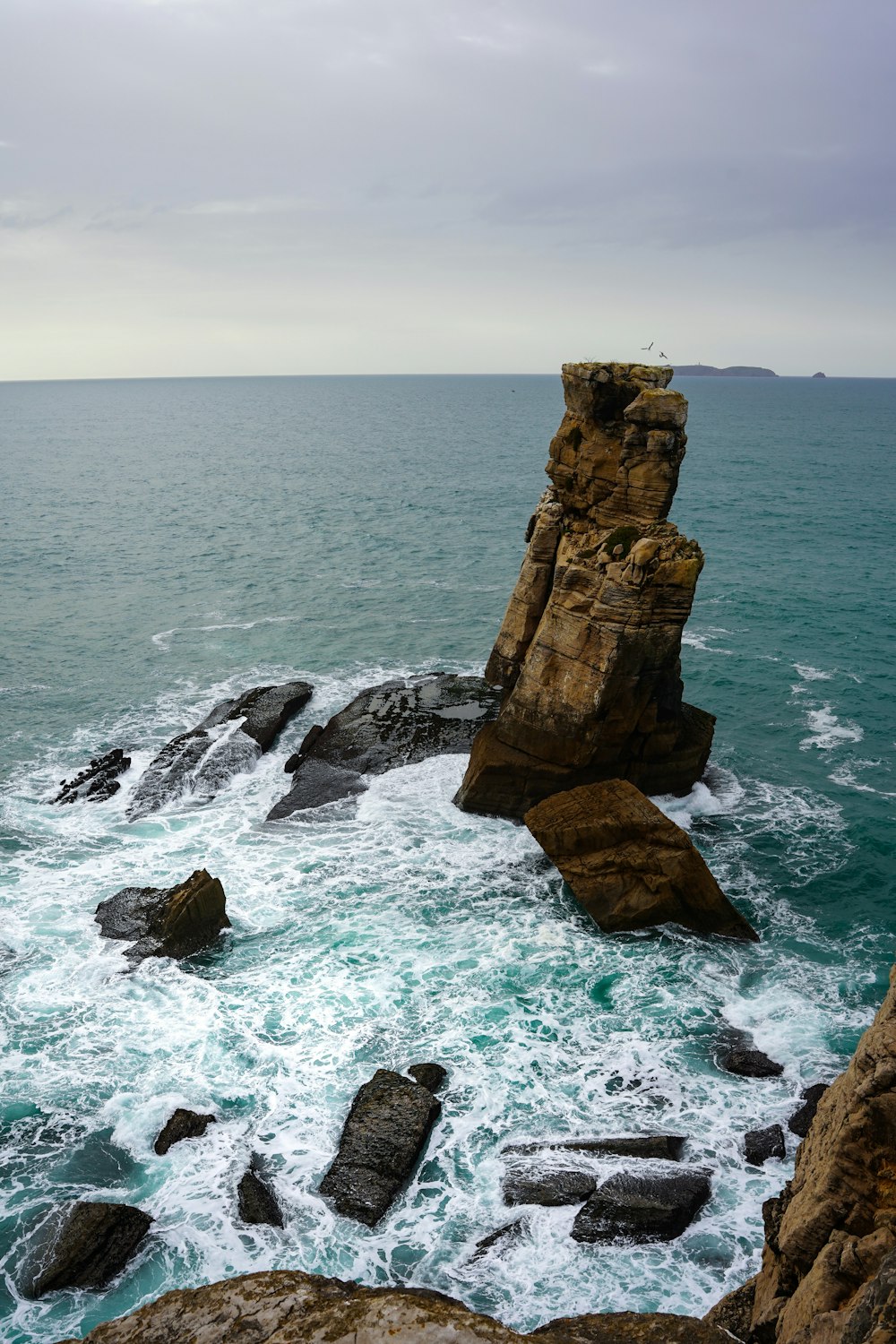 a rocky cliff with a body of water in the background