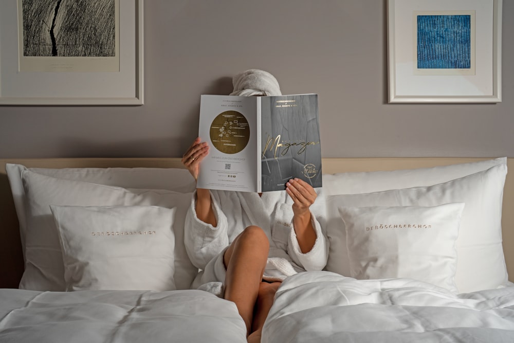 a person reading a book on a bed