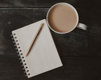 a cup of coffee and a pen on a table