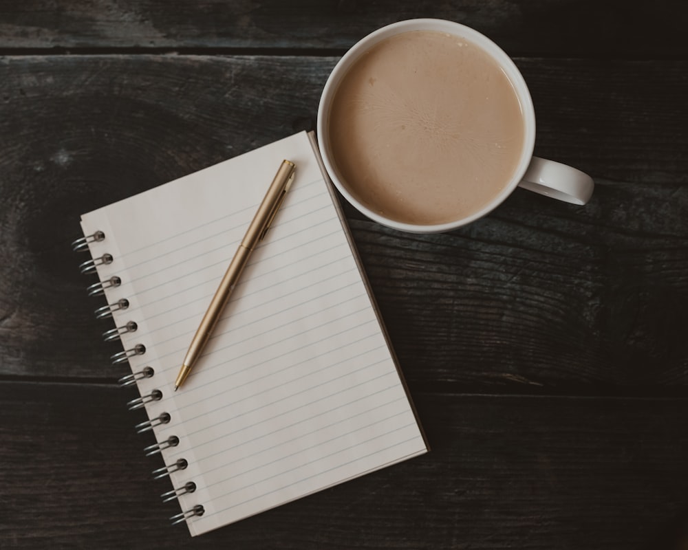 a cup of coffee and a pen on a table