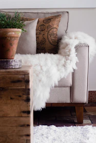 A serene corner with a cozy armchair, neutral tones, and a calming sage green throw.