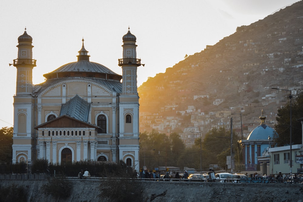 a large white building with a gold domed roof and a mountain in the background