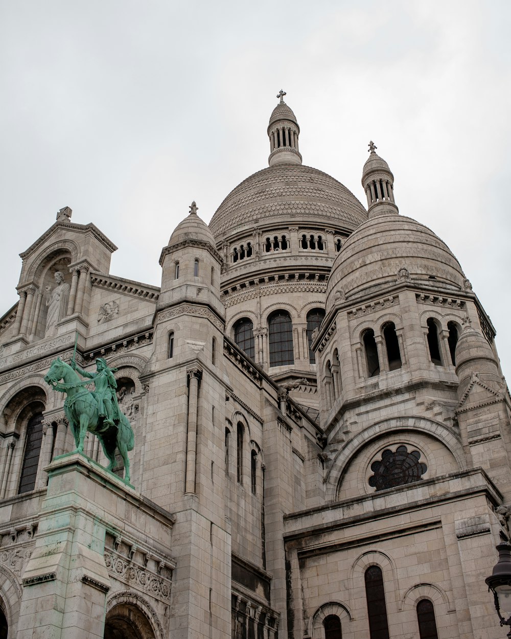 un gran edificio de piedra con una estatua frente a él con Sacré-Cœur, París al fondo