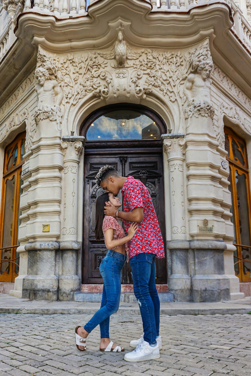 a man and woman kissing in front of a building