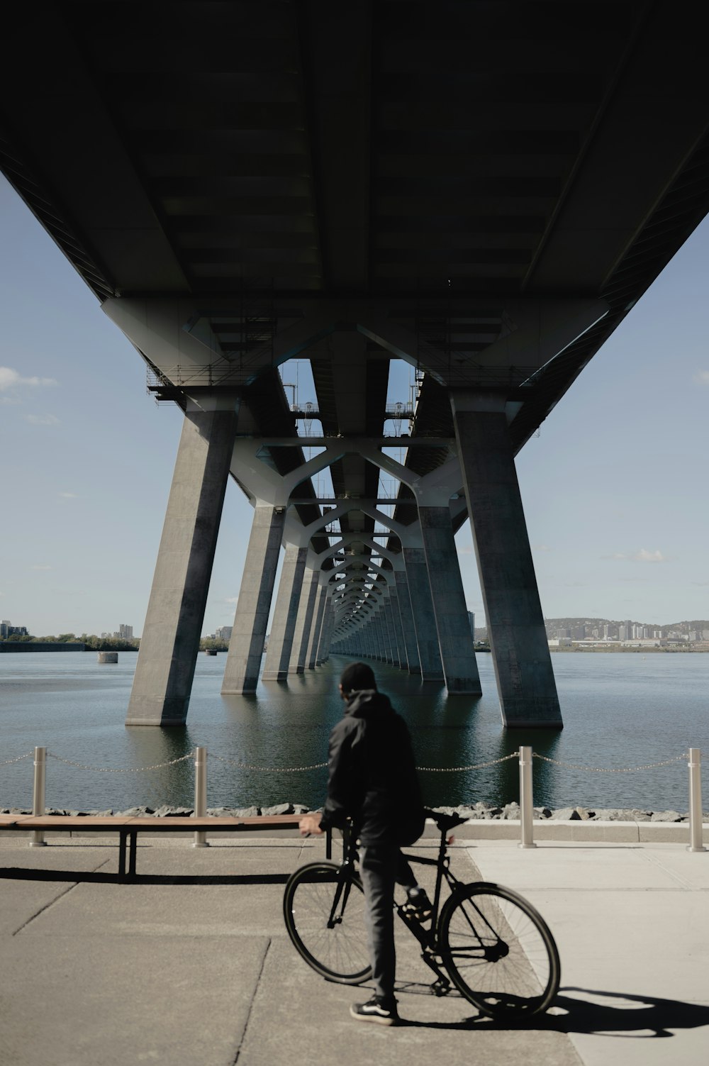 a person standing next to a bicycle under a bridge