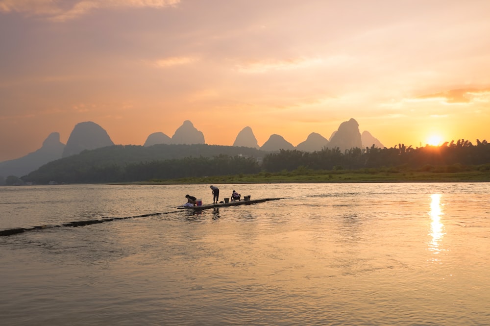 a group of people rowing a boat with Li River in the background
