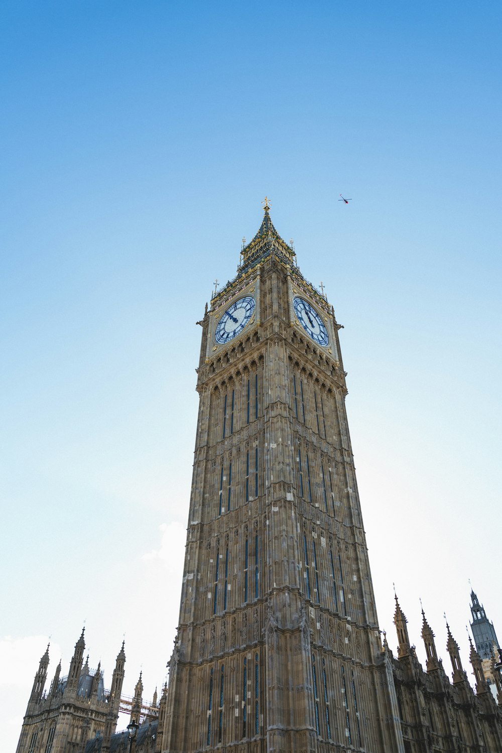 a clock tower with a weather vane with Big Ben in the background