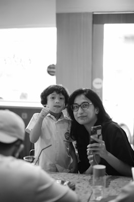 A smiling African Canadian mother helping her child with homework in a cozy home setting.