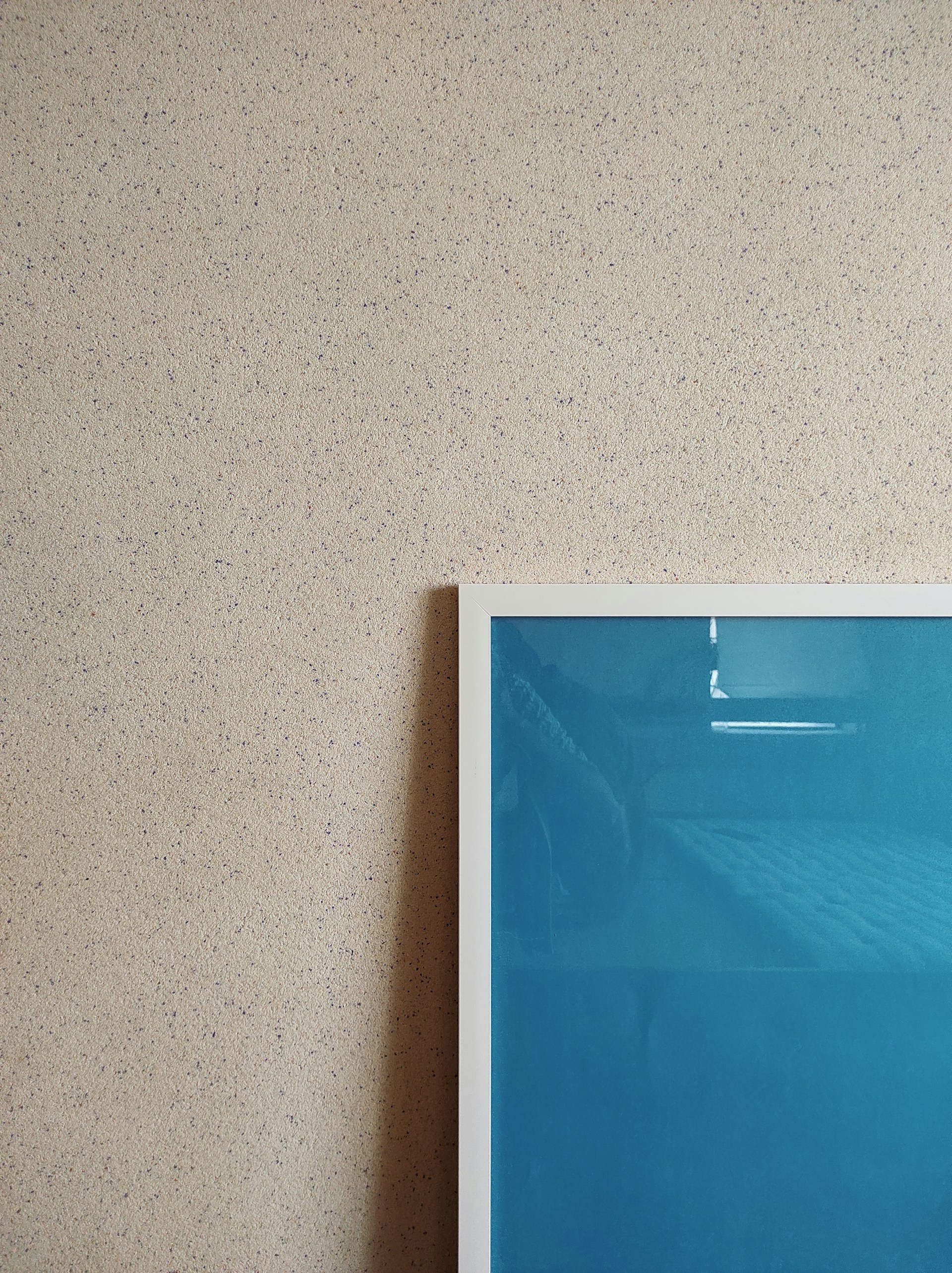 Close-up of a muted earth tone AI art piece with delicate textures, hanging against a warm white wall that enhances its quiet luxury feel.