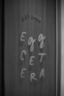 Wooden background with the phrase 'Egg Cetera' spelled out in a playful font using raised letters. Above, 'est 2020' is displayed in a similar style.