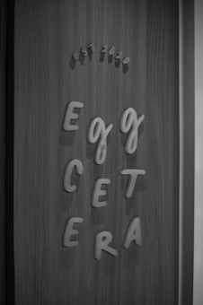 Wooden background with the phrase 'Egg Cetera' spelled out in a playful font using raised letters. Above, 'est 2020' is displayed in a similar style.