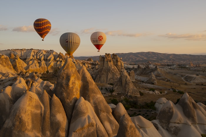 Hot air balloons floating over the dramatic rocky landscape of Cappadocia at sunrise