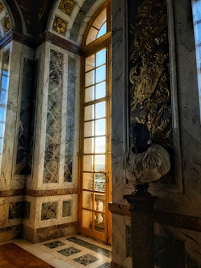 Elegant living room with marble floors and golden decorative elements, bathed in natural light.
