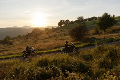 Group of motorcyclists riding through a scenic mountain road at sunset.