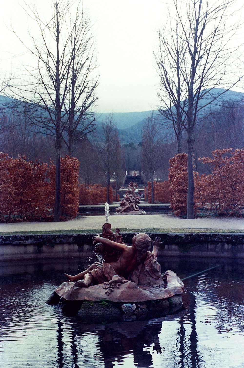 a statue of a man and a woman sitting on a rock in a pond