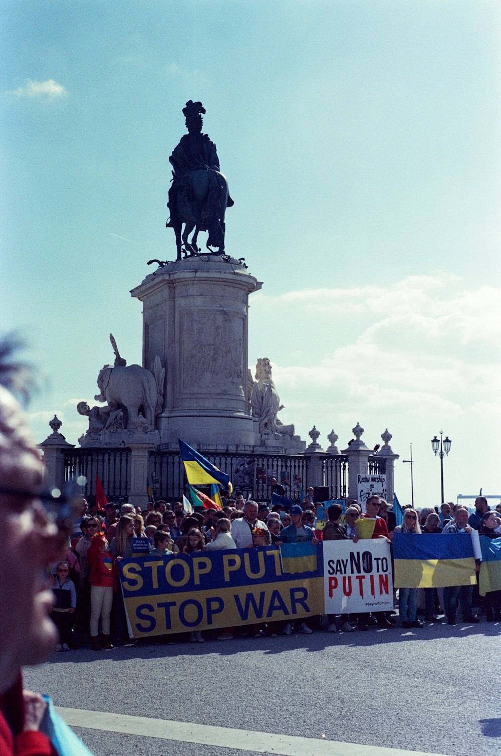 a group of people holding a sign in front of a statue