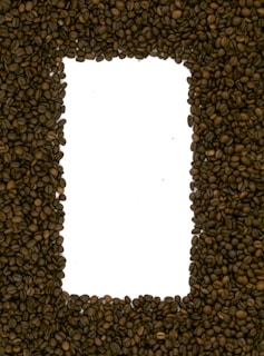 A rectangular frame made from dark brown coffee beans, with a white background visible in the center.
