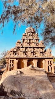 An ancient stone temple nestled among tall trees, showcasing intricate carvings.