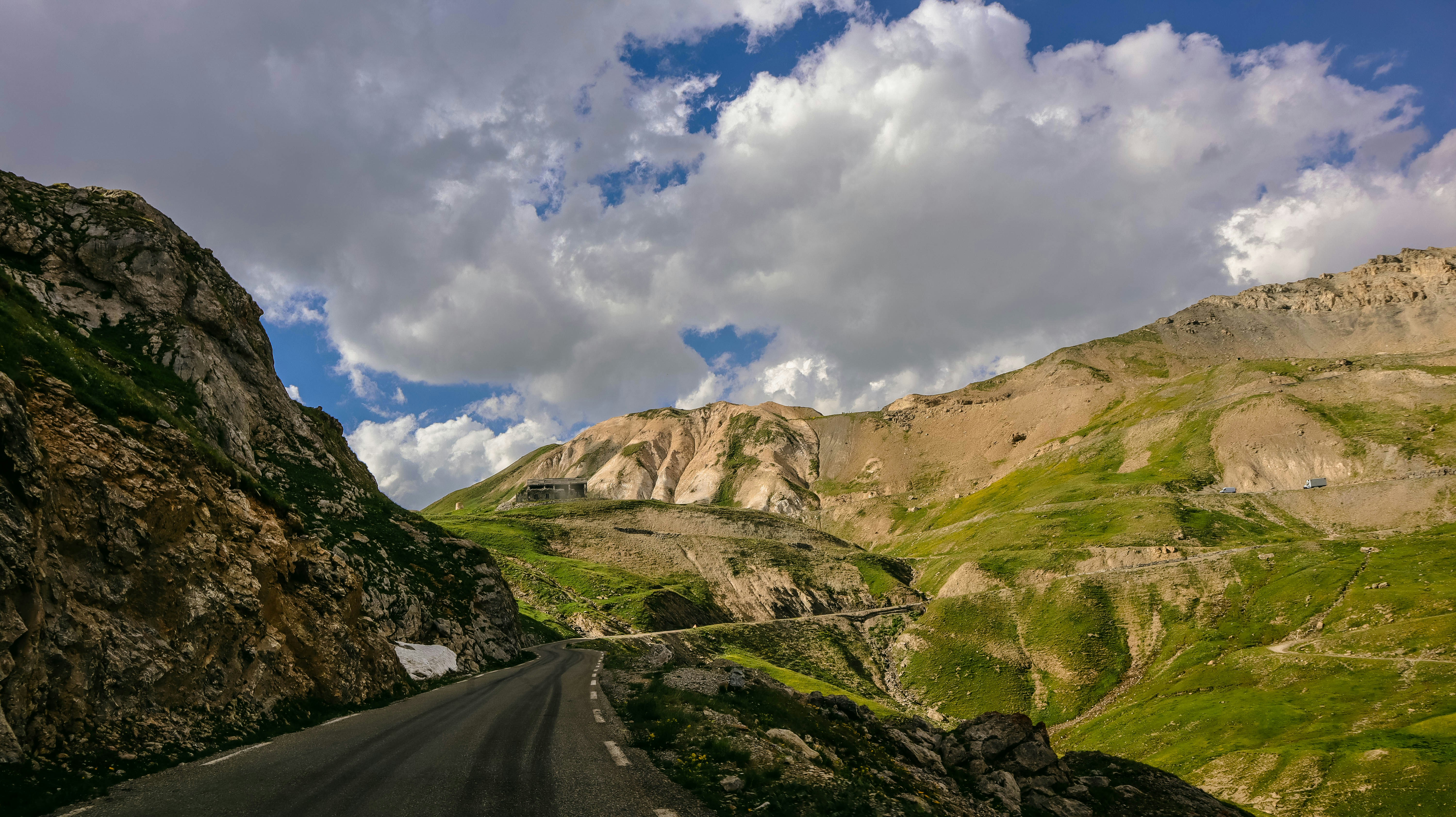 Cinematic adventure road trip scene with winding mountain highway and dramatic sky