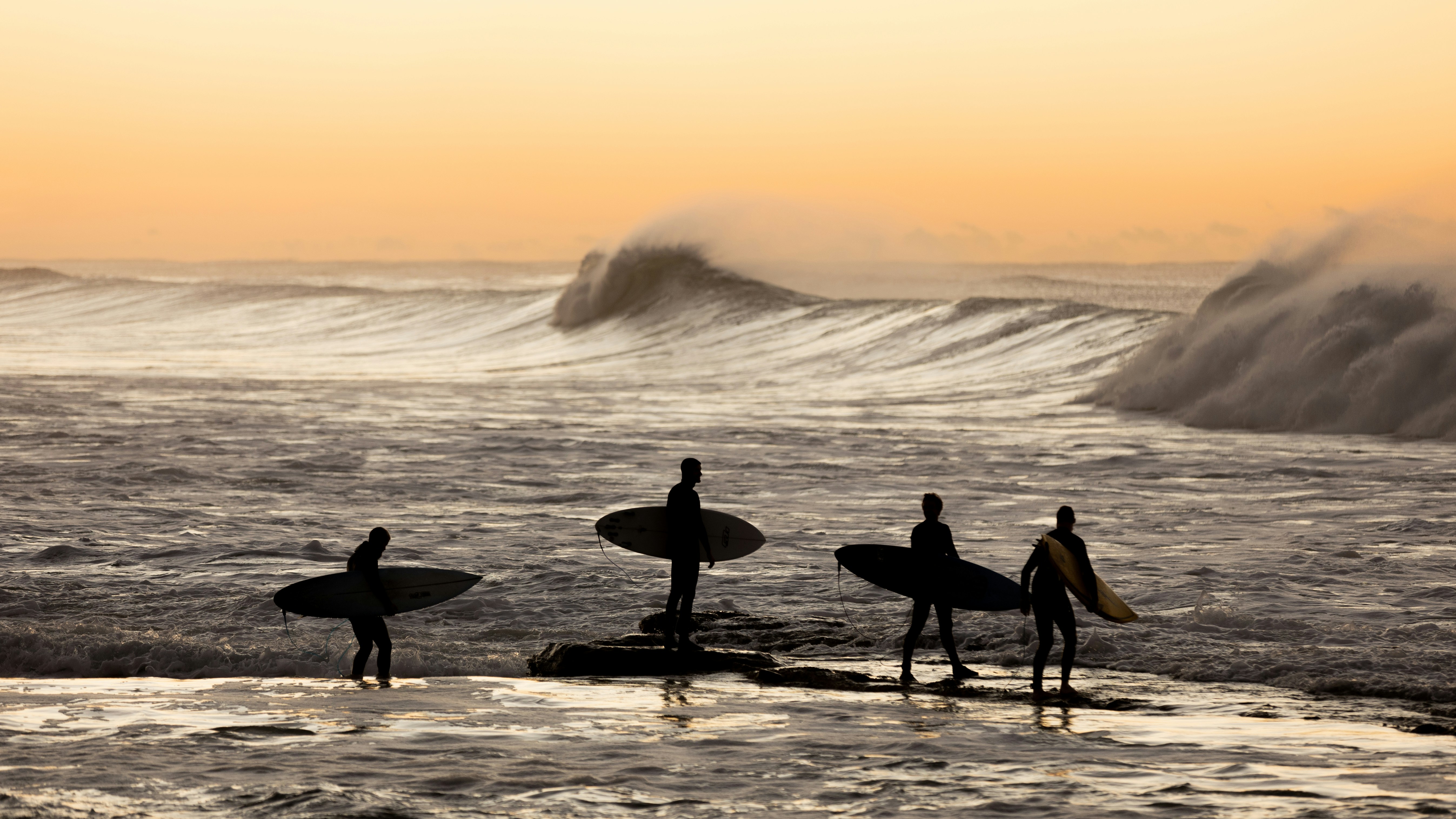 um grupo de surfistas caminhando na praia
